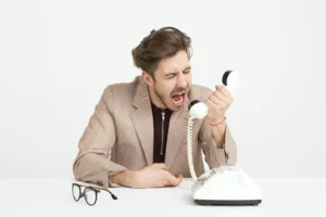 A tired and frustrated man yelling at the phone because things are not going the intended way